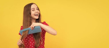 Mutlu çocuk uzun saçlarını tarıyor. Kuaför. Kızın dalgalı saç fırçası var. Gençlerin saç stili. Çocuk saç bakımı, yatay poster. Kopyalama alanı olan başlık