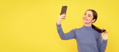 İzole edilmiş yüz portresi, fotokopi alanı olan pankart. Gülümseyen kadın akıllı telefondan selfie çekiyor, selfie.