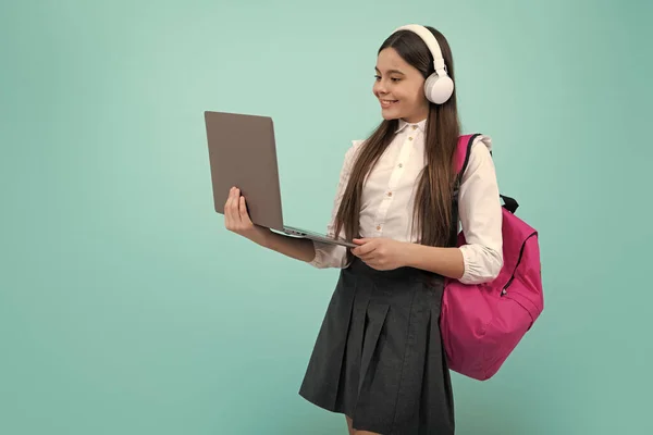 stock image Back to school. Teenager schoolgirl in school uniform with bagpack, headphones and laptop. School children on isolated blue background