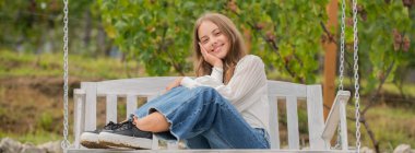 Gülümse çocuk parkta salıncakta oturuyor, mutluluk.