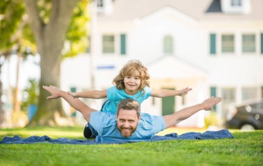 glad father with son relax together on green park grass, parenting.