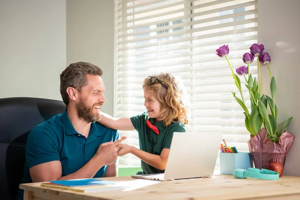 stock image happy dad helping his school son child in glasses study with computer at home, study online.