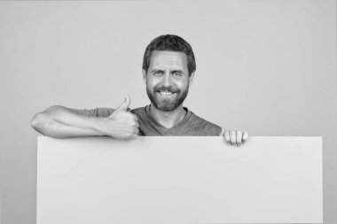 Reklam için fotokopi alanı olan bir adam. Reklamcılık. Duyuru. Alışveriş indirimi. ürün sunumu. Sarı kağıdın arkasındaki erkek. İşe yarar bilgiler. Kağıt pankartlı adam. başparmak yukarı.