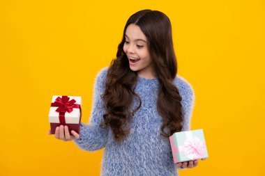 Amazed teenager. Child with gift present box on isolated studio background. Gifting for kids birthday. Excited teen girl