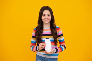 Teenage girl with shampoos conditioners or shower gel. Kids hair care cosmetic product, shampoo bottle. Happy teenager, positive and smiling emotions of teen girl