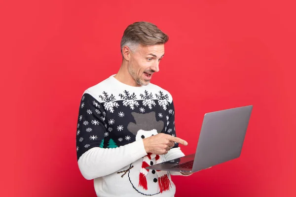 Człowiek Laptopem Mężczyzna Swetrze Świątecznym Kapelusz Mikołaja Czerwonym Tle — Zdjęcie stockowe
