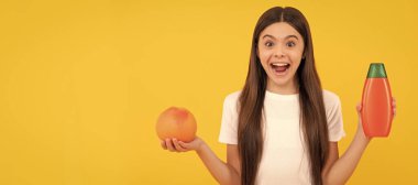amazed child hold shampoo bottle and grapefruit on yellow background, citrus. Banner of child girl hair care, studio poster header with copy space