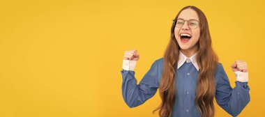 Happy back to school child show winning gesture yellow background, winner. Child face, horizontal poster, teenager girl isolated portrait, banner with copy space