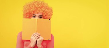 Kitap kurdu eğitimde. Tuhaf kitap kurdu sarı arka plan. Mutlu çocuk kitapla yüzünü kapatıyor. Partideki komik genç çocuk, afiş başlığı fotokopi alanı