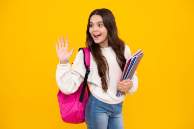 Okula dönelim. Liseli kız, sarı izole stüdyo geçmişi üzerine kitap tutuyor. Okul ve eğitim kavramı. Okul üniformalı ergen kız. Mutlu yüz, pozitif ve gülümseyen duygular.