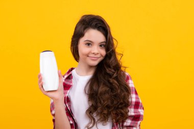 Şampuan kremi kullanan bir çocuk. Günlük kozmetik bakım. 12, 13, 14 yaşlarındaki ergen çocuğun elinde saç ve cilt bakımı şişesi var. Güzellik sağlığı ve kozmetik ürünleri. Mutlu genç