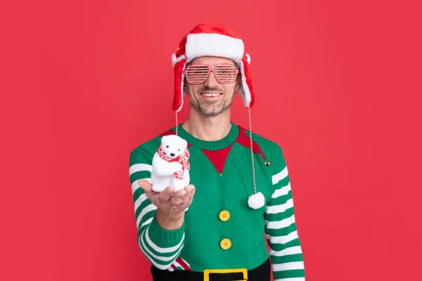 新年快乐 快乐的圣诞节 身穿精灵服装 头戴圣爪帽的快乐男人 戴著派对眼镜的家伙展示了红色背景的圣诞装饰雪人 — 图库照片