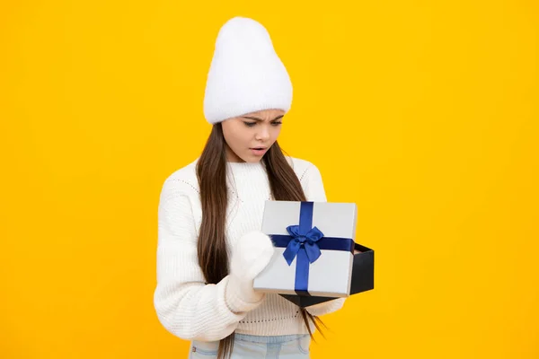 Funny kid girl in winter wear holding gift boxes celebrating happy New Year or Christmas. Winter holiday. Angry teenager girl, upset and unhappy negative emotion