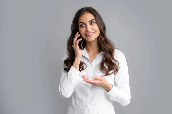 stock image Smiling charming brunette woman talking on mobile phone, isolated over gray background. Girl with mobile cell phone