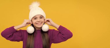 Sarı arka planda kartopları olan şapkalı neşeli çocuk. Noel çocuğu, stüdyo çocuğu kışın fotokopi çekilen portresi
