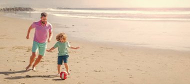 Baba ve oğul plajda futbol ya da futbol oynuyor. Mutlu baba ve oğul yaz kumsalında top ve arkadaşlıkla futbol oynuyorlar..