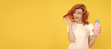 Beautiful woman with organic shampoo over light yellow background. curly hair. Woman isolated face portrait, banner with copy space