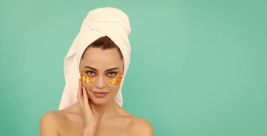 Genç kızın yüzünde havluyla kolajen altın göz bantları var. Boşluğu kopyala.