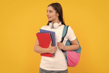 Pozitif öğrenci defteri. Sarı arka planda defteri tutan kız. Kitapları ve kulaklıkları olan özel bir öğretmen. Okula dönüyorum. modern eğitim kavramı.