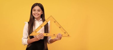 smiling kid in school uniform hold mathematics triangle for measuring, math. Banner of school girl student. Schoolgirl pupil portrait with copy space