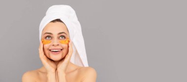 Güzel bir kadın, izole edilmiş bir yüz portresi, taklit alanı olan bir afiş. En güzel parıltı. Nemlendirici cilt. Kozmetoloji. Havlu bantlı genç kadın