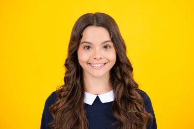 Portrait of beautiful happy smiling teenage girl on yellow studio background