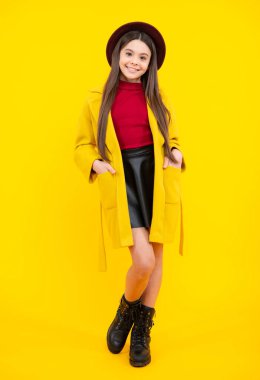 Sonbahar giysileri. Esmer genç kızın tam boy fotoğrafı sarı arka planda izole edilmiş günlük kıyafetler giyer. Mutlu ergen portresi. Gülümseyen kız