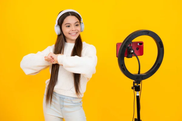 stock image Music kids blog. Blogging, videoblog. Teenager child blogger with phone recording video on isolated yellow studio background. Influencer teen girl speaking in front of smartphone