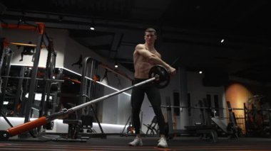 Spor salonundaki kaslı sporcular kara mayını egzersizi yapar. Spor salonunda halter mayınlı bir sporcu. Spor salonunda halter ekipmanlı bir sporcu..