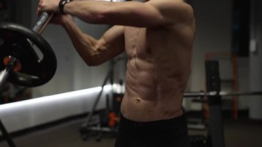 Spor salonundaki yakın plan atletik adam kara mayını egzersizi yapıyor. Spor salonunda halter mayınlı sporcu. Spor salonundaki halter ekipmanlı atletik adam..