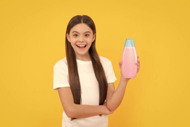 amazed kid hold hair conditioner bottle on yellow background, beauty.