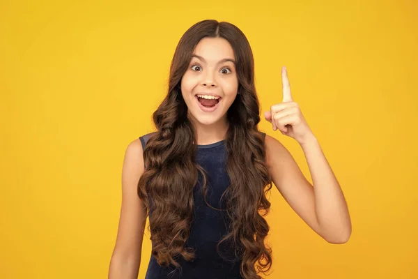 stock image Excited face, cheerful emotions of teenager girl. Portrait of young teenager pointing up with finger, isolated on yellow background. Funny school girl, kid genius, nerd young student