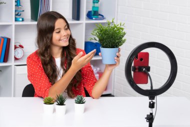 Young blogger girl recording video for blog. Teen girl speaking in front of camera for vlog. Teenager working as blogger, recording video tutorial for blog. Happy girl , positive and smiling emotions