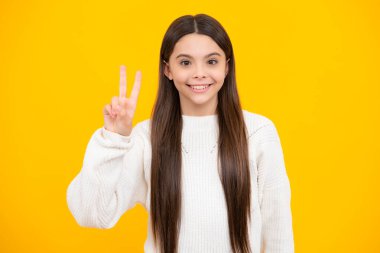 Teenager child girl showing fingers victory sign. Number two, v-sign symbol isolated on yellow background