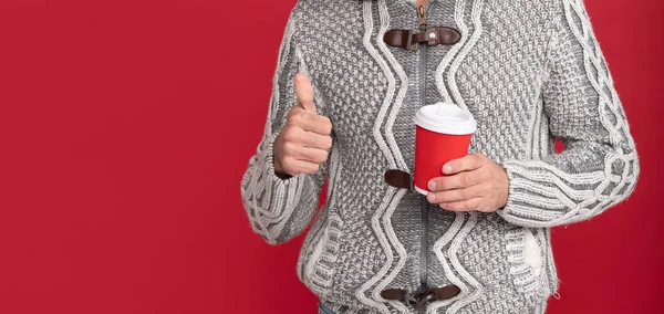 스웨터를 귓바퀴 모자를 남자가 아침에 손가락이 나타나는 배경의 커피를 마십니다 — 스톡 사진