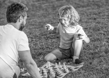 Ebeveynlik ve çocukluk. Şah mat. Birlikte vakit geçirmek. Stratejik ve taktiksel. Özel ders. Baba ve çocuk mantık oyunu oynuyorlar. Baba ve neşeli oğul parkta satranç oynuyorlar. Babalar günü. Mutlu aile.