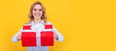 Sarı arka planda büyük hediye kutusu olan neşeli bir kadın. İzole edilmiş yüz portresi, taklit alanı olan pankart