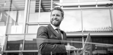 Resmi takım elbiseli mutlu sakallı iş adamı internette çalışıyor, serbest çalışıyor..