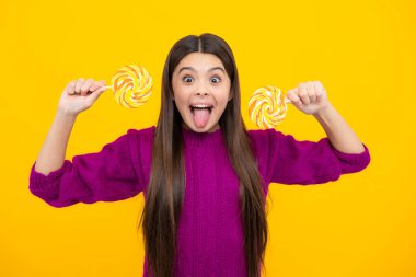 Heyecanlı bir yüz. Sarı izole edilmiş arka planda lolipopu olan havalı bir genç çocuk. Tatlı çocukluk hayatı. Lezzetli lolipop şekerli genç kız. Şaşırtıcı bir ifade, neşeli ve mutlu.