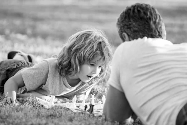 父母身份和童年 检查伙伴 花时间在一起 战略和战术 爸爸和孩子玩逻辑游戏 父亲和好奇的儿子在公园的草地上下棋 父亲节 家庭日 — 图库照片