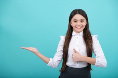 Onun yakın plan portresi. Güzel, çekici, neşeli, şaşkın kız. Mavi arka planda izole edilmiş fotokopi alanını işaret ediyor. Kopyalama alanını düzenle