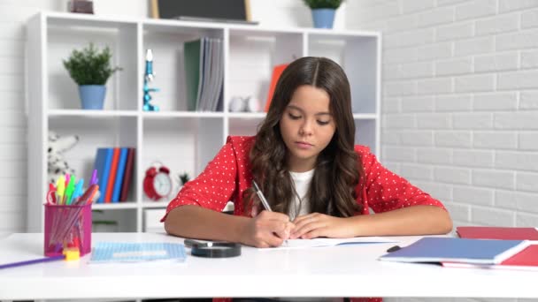真剣な女の子の子供の書き込みでコピーブックを行う宿題で学校の机 — ストック動画