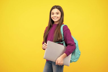 Schoolchild, teenage student girl with laptop on yellow isolated studio background. Children school and education concept