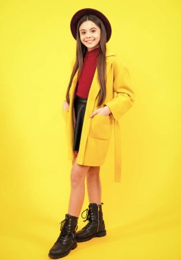 Elegant fashion teenager child girl in autumn coat posing in studio. Trends kids clothes. Happy teenager portrait. Smiling girl