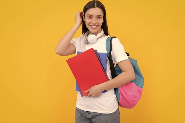 コピーとヘッドフォン付きの私立教師です 学校に戻って 現代教育の概念です 陽気な生徒がノートを持ってる 黄色の背景にノートを持っている女の子 — ストック写真