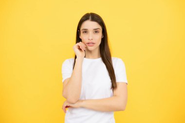 Zevkli bir kadın model tatmin edici görünüyor. Sarı arka planda izole edilmiş güzel bir kadının stüdyo portresi