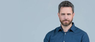 Sıradan tişörtlü sakallı bir adam. Gri arka planda aralık ölçer fotoğraf makinesi, fotoğrafçılık. İnsan yüzü portresi, kopyalama alanı olan pankart