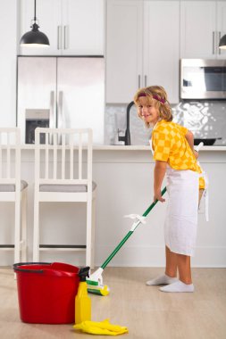 Çocuk yerleri temizliyor. Ev işlerine yardım eden, evi temizleyen çocuk portresi. Oda servisi, ev işleri.