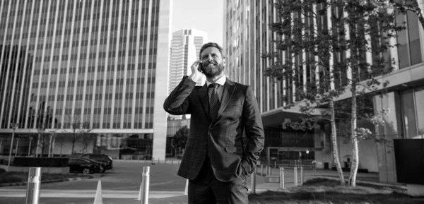 stock image confident entrepreneur in businesslike suit talking on phone outside the office, employee.