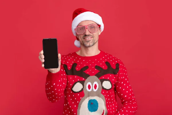 온라인으로 인사해 스웨터입고 클라우스 모자쓴 배경에 핸드폰 화면을 Xmas Guy — 스톡 사진